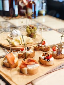 Tasty assortment of cheese, salmon, and olives on a wooden board, perfect as a party snack.