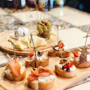 Tasty assortment of cheese, salmon, and olives on a wooden board, perfect as a party snack.